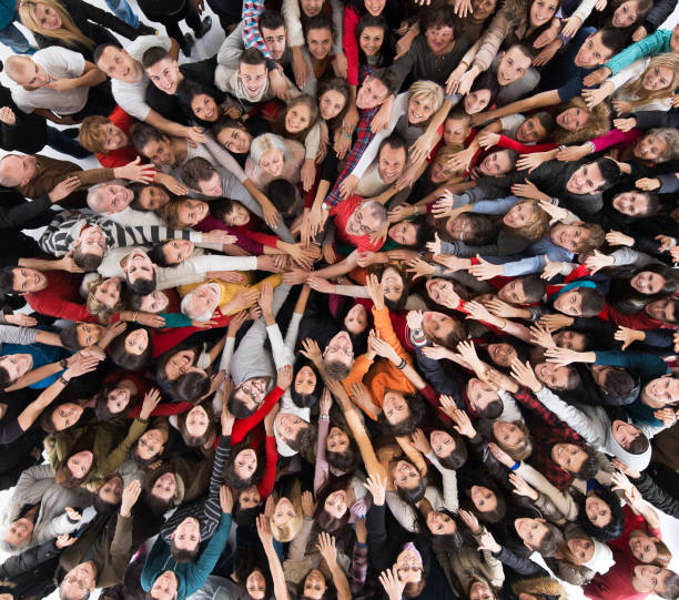 au-dessus de vue de la foule des gens rejoignant les mains dans l’unité. - holding hands human hand holding multi ethnic group photos et images de collection