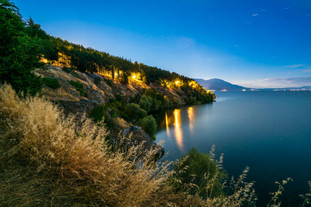Ohrid, Republic of Macedonia - July 20, 2016:   view showing Ohrid Lake , trees, rocks and lights at night can be seen on the background