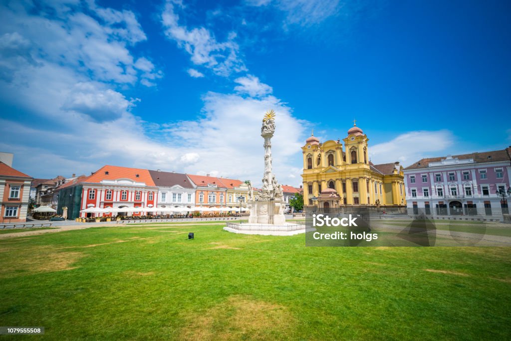 Timisoara Union Square, Old buildings and Roman Catholic church, Statue of the Holy Trinity, Timisoara, Romania, Europe Timisoara, Romania - July 9, 2016: Timisoara  view showing Union Square, old buildings and Roman Catholic church, Statue of the Holy Trinity, outdoor cafes and people passing and sitting can be seen on the background Timisoara Stock Photo