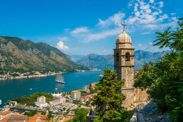Kotor, Montenegro - July 24, 2016: view showing Kotor Cruise Port and Lake, bell tower,  rock mountains, trees, street cars, buildings and houses can be seen on the background