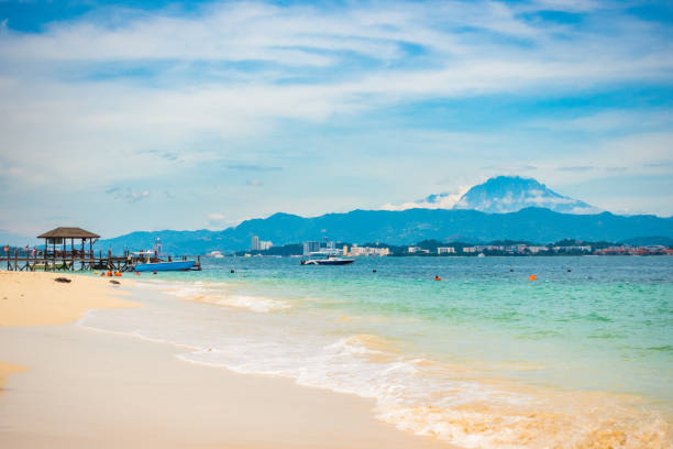 Kota Kinabalu, Malaysia - September 17, 2016: Kota Kinabalu  view showing Mamutik Island, bridge, mountains, trees, boats in the sea and people swimming can be seen on the background