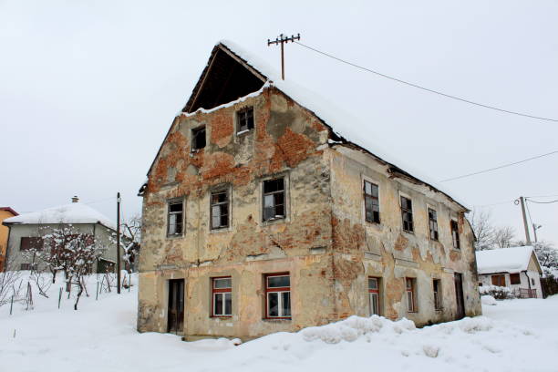 istock Abandoned house with broken windows and fallen bricks covered in snow 1079561130