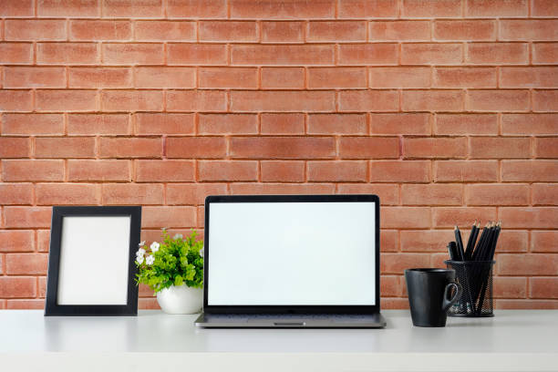 istock Mockup laptop computer, photo frame,  coffee and plant decoration on office table and brick wall background. 1079562566