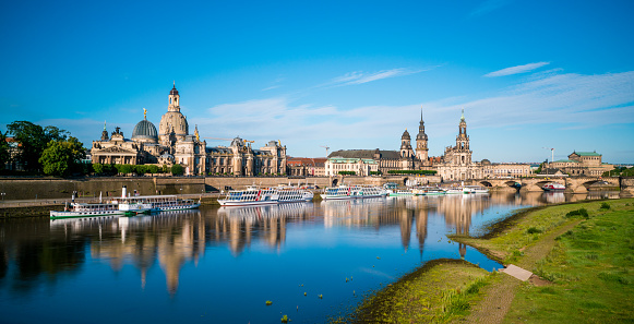 Dresden, Germany - July 3, 2016:   view showing Dresden river, churches and harbor  cruises, trees can be seen on the background