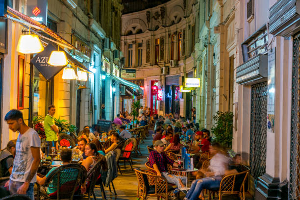 Cafes within the Pasajul Macca- Vilacrosse Arcade at night in Bucharest, Romania, Europe Bucharest, Romania - July 15, 2016: Bucharest  view showing Cafes within the Pasajul Macca- Vilacrosse arcade, apartment buildings and people sitting in the cafes can be seen at night bucharest people stock pictures, royalty-free photos & images