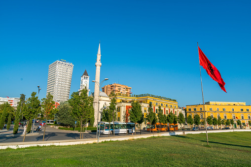 Tirana, Albania - July 22, 2016:   view showing The Main Square of Tirana, towers, buildings, flag, buses, street cars and people can be seen on the background