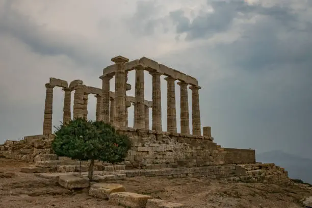 Ruins of the Temple of Poseidon with cloudy sky at Sounion, Greece