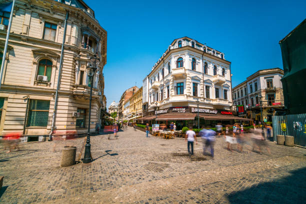 Bucharest, Romania - July 14, 2016:  view showing Bucharest Old town square , buildings, outdoor cafes, market stall, apartment buildings and people walking on the street
