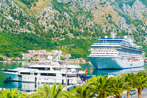 Kotor, Montenegro - July 24, 2016: view showing Kotor Cruise Port and Lake, rock mountains, trees, street cars, buildings and houses can be seen on the background