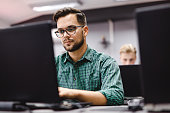 Male student studying over laptop at computer lab.