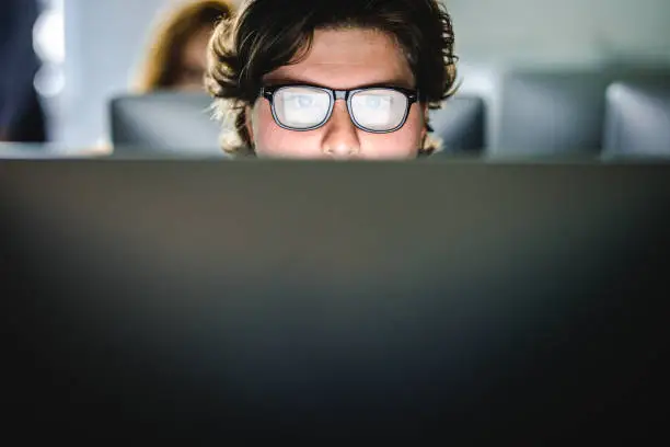 Photo of Male student learning a lecture over desktop PC at computer lab.