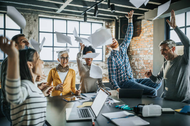 fröhliche geschäftsteam kotzte papiere in der luft im büro. - man throwing papers stock-fotos und bilder