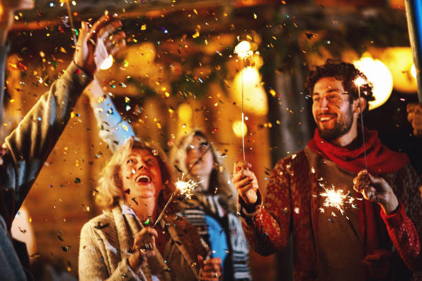 Family New Year's Eve Party. Family dancing and celebrating New Year's Eve outdoors. Confetti in focus. christmas excitement stock pictures, royalty-free photos & images