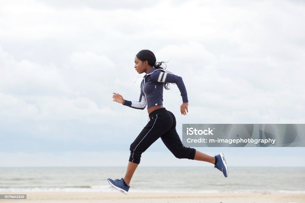 ビーチで走っているアフリカ系アメリカ人の女性の側面の肖像画 - 走るのロイヤリティフリーストックフォト