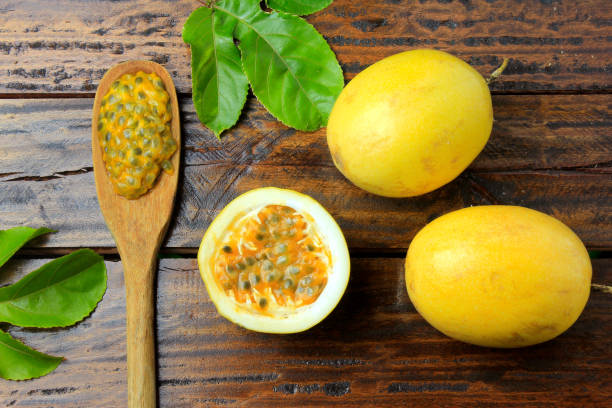 istock passion fruit pulp on the wooden spoon next to passion fruit on wooden table. Top view 1079628340