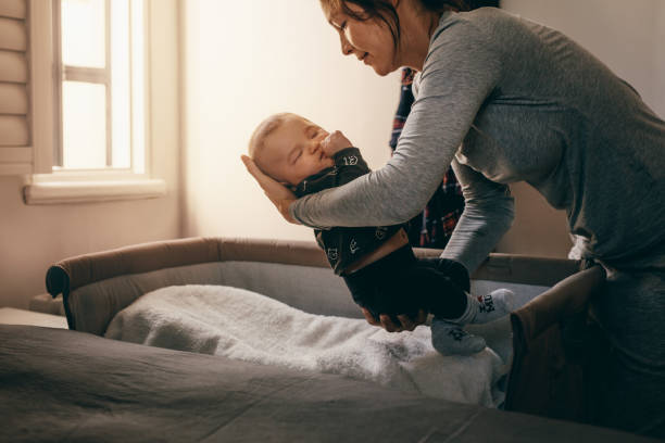 madre pone a su bebé a dormir en una cuna cabecera - baby mother sleeping child fotografías e imágenes de stock