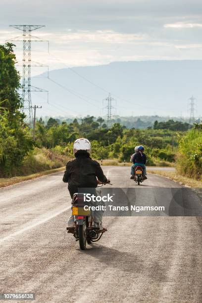 Motorcycle Travels On The National Highway T 16 From Salavan To Pakse Laos Asphalt Road On Bolaven Plateau At Evening Laos People Returning Home After Work Summer Season Transportation Stock Photo - Download Image Now