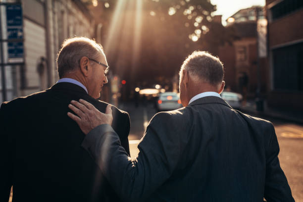senior zakenman lopen samen buiten - rugzaken stockfoto's en -beelden