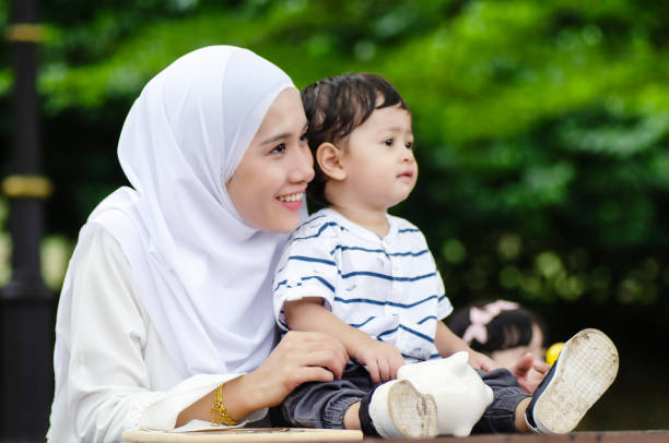 istock Family concept, young mother with her son sit on bench under the tree 1079673650