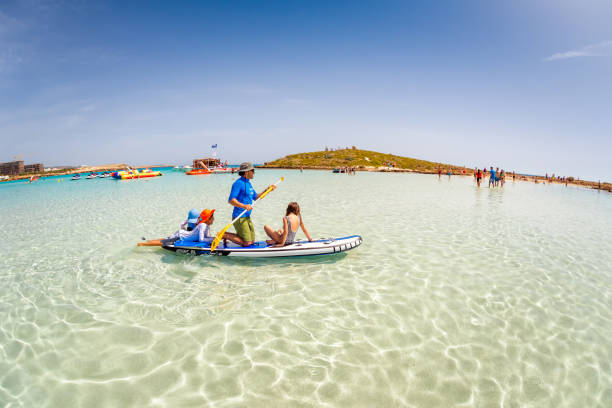 AYIA NAPA, CYPRUS - APRIL 07, 2018: Father with kids having fun on stand up paddle board at Nissi beach