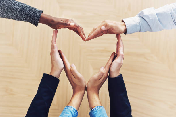 Teamwork is at the heart of success High angle shot of a group of unidentifiable businesspeople forming a heart shape with their hands heart hands multicultural women stock pictures, royalty-free photos & images