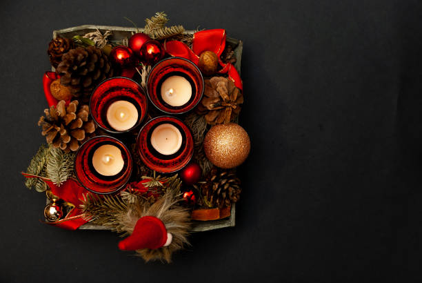 Top view of Advent wreath on black background with some copy space - three candles burning - third advent Top view of Advent wreath with four candles, fir tree, christmas balls, a dwarf and a fir cone on black background advent candle wreath christmas stock pictures, royalty-free photos & images