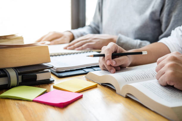 istock High school tutor or college student group sitting at desk in library studying and reading, doing homework and lesson practice preparing exam to entrance, education, teaching, learning concept 1079712094