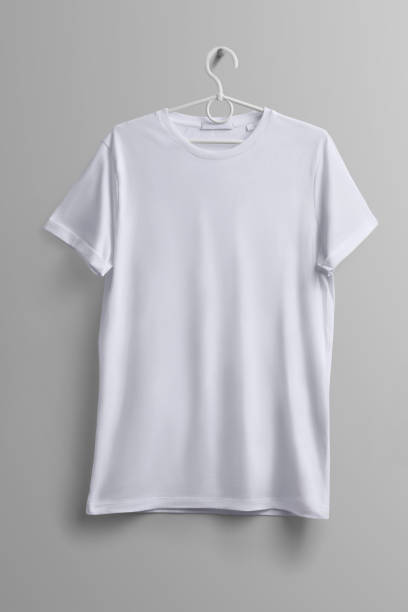 istock White T-shirt hanging on a plastic hanger with shadows on a studio gray background. 1079733186