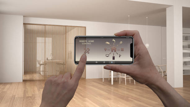 istock Remote home control system on a digital smart phone tablet. Device with app icons. Interior of minimalist white and wooden living room in the background, architecture design 1079734118