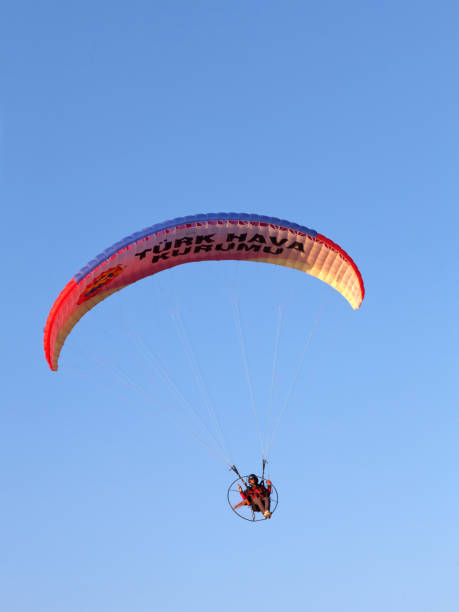 parapente survolant au coucher du soleil le lagon bleu à oludeniz, turquie - skydiving air aerial view vertical photos et images de collection
