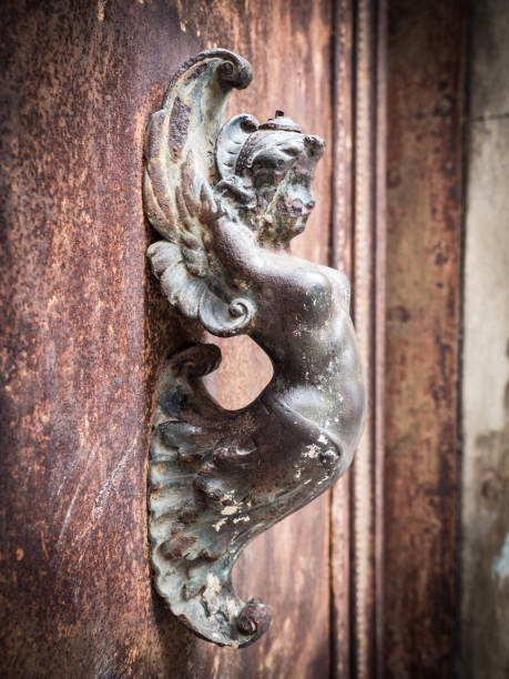Mermaid-shaped handle of an ancient portal of an old building.