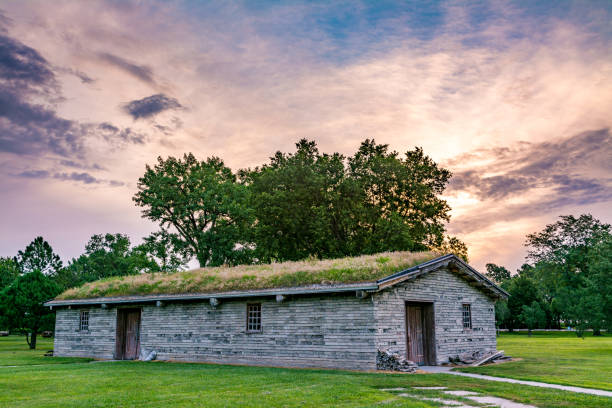 Old antique building in Nebraska with a sod roof surrounded by trees Long building made from mud bricks with a sod roof and sunrise kearney nebraska stock pictures, royalty-free photos & images