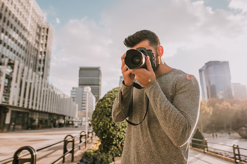 A young man using a modern DSLR camera in a city