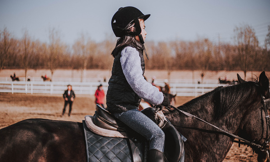 Young Asian girl riding her horse