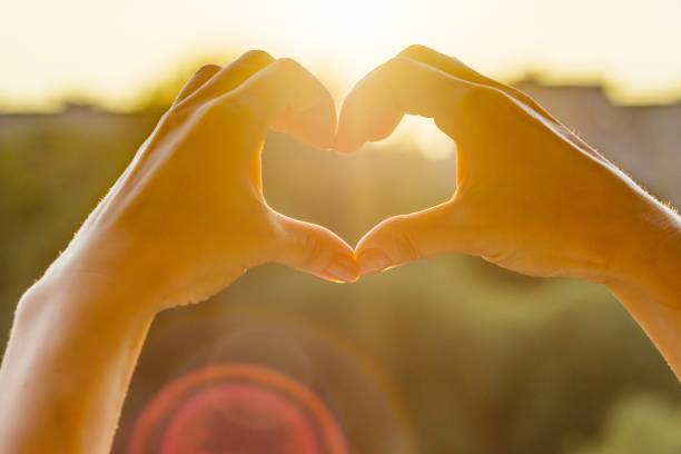 istock Hands showing gesture heart, background evening sunset, city silhouette 1079776978