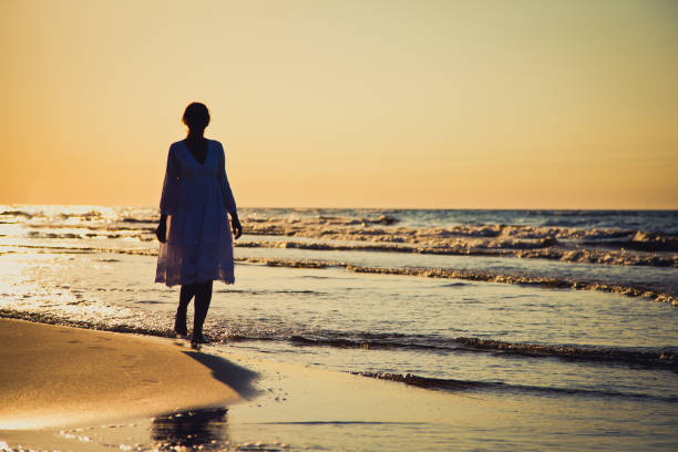 istock Woman walking on beach 1079778962