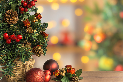 Close-up of Christmas tree with colorful ornaments in the foreground and Christmas decoration blurred in the background