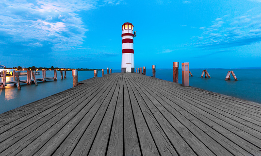 Morning view of lighthouse tower and walking wooden path