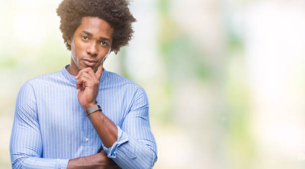 istock Afro american man over isolated background with hand on chin thinking about question, pensive expression. Smiling with thoughtful face. Doubt concept. 1079802238