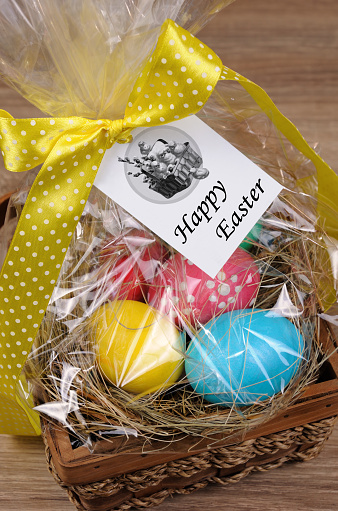 Colorful  eggs stacked hay in cellophane gift basket for Easter
