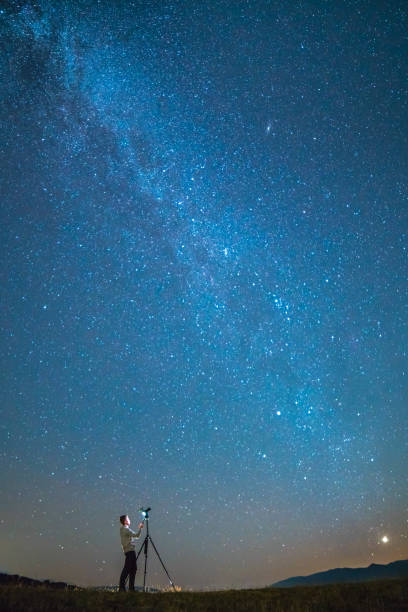 istock The photographer with a camera stand on the starry sky background. night time 1079826056