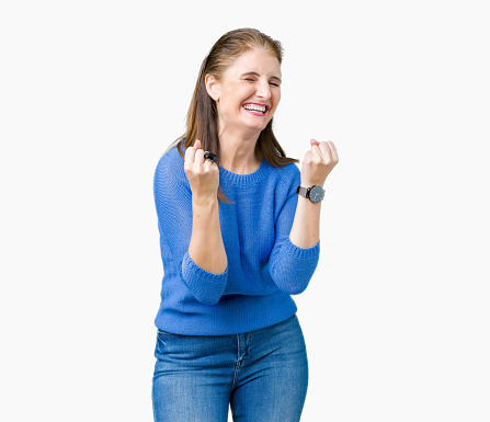 Beautiful middle age mature woman wearing winter sweater over isolated background very happy and excited doing winner gesture with arms raised, smiling and screaming for success. Celebration concept.