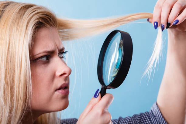 istock Woman looking at hair through magnifying glass 1079833012