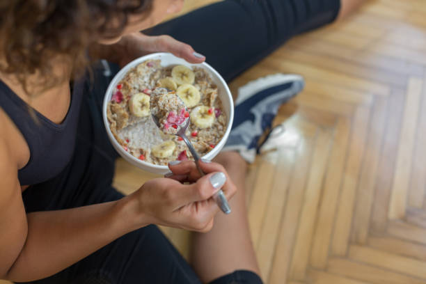 jeune femme manger une avoine après une séance d’entraînement - oatmeal breakfast healthy eating food photos et images de collection