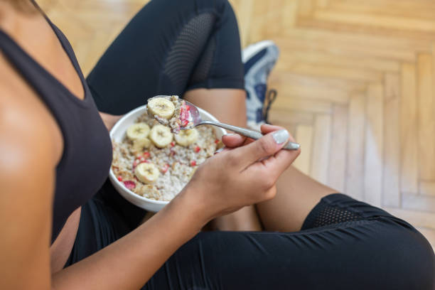 young woman eating a oatmeal after a workout - eating women breakfast cereal imagens e fotografias de stock