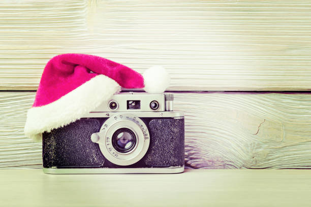 istock Old camera in santa hat on wooden background. Instagram filter effect. 1079837890