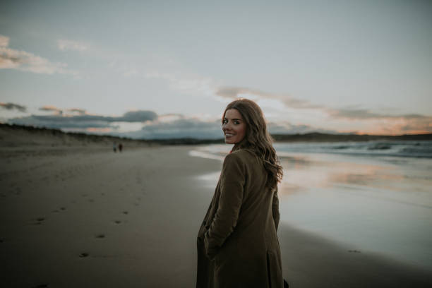istock Young woman walking over a beach in winter at sunset 1079838302
