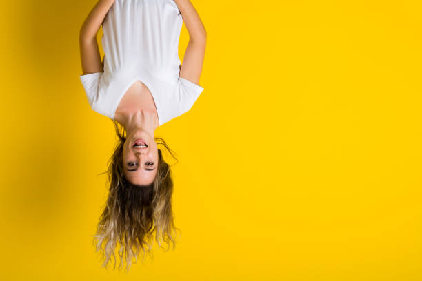 Beautiful young blonde woman jumping happy and excited hanging upside down over isolated yellow background Beautiful young blonde woman jumping happy and excited hanging upside down over isolated yellow background upside down stock pictures, royalty-free photos & images