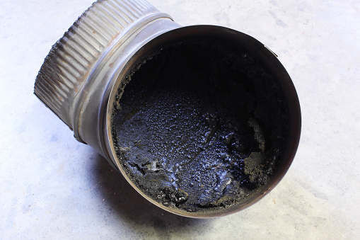 A buildup of black creosote in a chimney stove pipe.