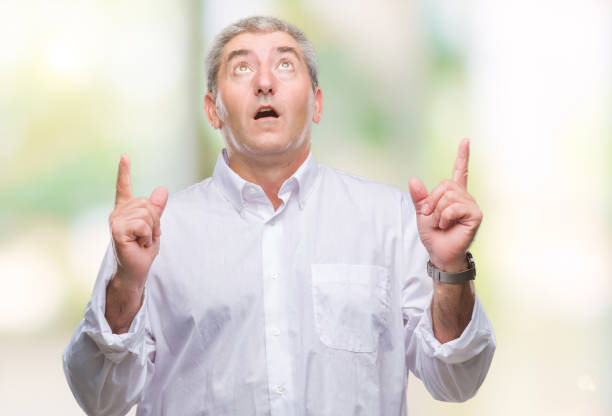 istock Handsome senior man over isolated background amazed and surprised looking up and pointing with fingers and raised arms. 1079855736